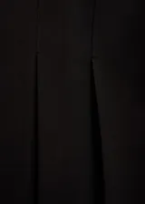 Minifalda negra de tejido fluido con diseño de tablas y tiro alto. Cuenta con forro interior y cierre de cremallera invisible en el lateral.
