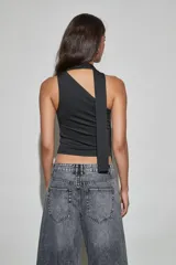 Top negro sin mangas con diseño de cuello halter y detalle de tira larga lateral. Presenta un ajuste entallado con frunces en los laterales.