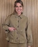 Sobrecamisa de pana color tostado, con cuello camisero, cierre frontal de botones, bolsillos aplicados en el frente y detalle de volado en el ruedo.