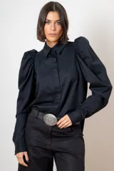 Camisa de algodón color marrón con mangas largas abullonadas, cuello clásico y cierre frontal oculto. Presenta botones decorativos con strass en los puños y en el cuello.