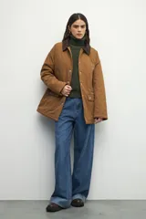 Campera color marrón con cuello de pana marrón oscuro, bolsillos con solapa y botones metálicos. Interior forrado con tela satinada capitoneada.