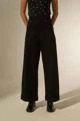 Pantalon de jean negro de corte ancho y tiro alto, con costuras verticales frontales y bolsillos laterales.