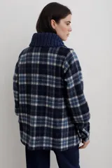 Camisa de paño de lana, color negro, con cuello tejido en contraste y cierre frontal de botones claros. Presenta bolsillos frontales y diseño de corte recto.
