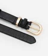 Cinturón femenino mediano de poliuretano negro con textura de cocodrilo (crocco). Posee una hebilla redondeada y trabillas metálicas de color dorado.
