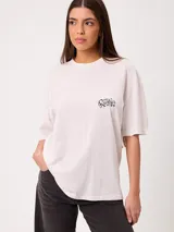 Remera de manga corta color blanco, de corte oversize, con gran estampado en la espalda de estilo gráfico y texto.