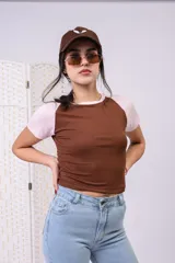 Remera estilo baby tee acanalada, de diseño bicolor con cuerpo marrón y mangas cortas rosadas tipo raglán.