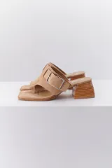 Sandalia color beige con tira ancha de cuero sobre el empeine, hebilla metálica plateada y taco geométrico de madera.