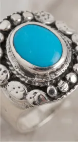 Anillo de plata 925 con piedra central ovalada de pasta de turquesa y diseño de borde texturizado con detalles circulares.