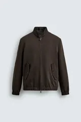 Cazadora de corte regular confeccionada en tejido de lana y algodón de origen italiano. Presenta cuello alto ajustable con botones, cierre frontal con cremallera de doble dirección, bolsillos laterales con solapa y puños y ruedo con acabado elástico.