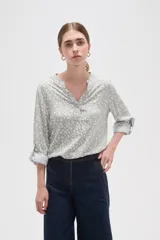 Blusa de viscosa con estampado floral pequeño, cuello mao con escote en V y cierre frontal parcial de botones. Presenta mangas largas con puños y un bolsillo frontal en el pecho.