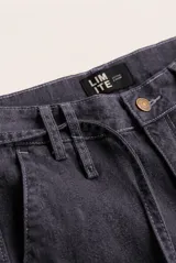 Jean tostado de corte wide leg, tiro medio con presillas y lazo ajustable en la cintura. Presenta bolsillos delanteros y traseros, costuras decorativas verticales y terminación desmechada en el ruedo.