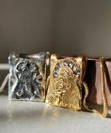 Collar dorado con dije rectangular con imagen religiosa y cristales azules.