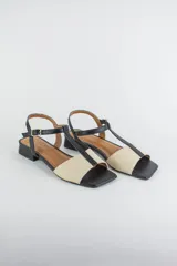 Sandalias de cuero combinadas en negro y marfil, con diseño de tiras en T, taco cuadrado bajo y pulsera con hebilla ajustable al tobillo.