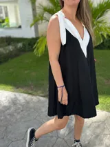 Vestido corto color beige, con escote en V con borde blanco, breteles anchos con lazos y corte holgado.