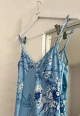 Vestido midi celeste con estampado floral en tonos azules y blancos, de breteles finos y corte al cuerpo.
