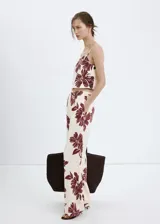 Pantalón de corte regular y tiro medio, con diseño fluido y estampado floral en color bordó sobre fondo beige.