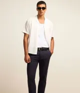 Pantalón de vestir color marrón, de corte slim y largo cropped. Confeccionado en tejido de algodón liso, con bolsillos laterales y traseros. Cierre frontal con botón y cremallera.