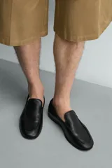 Mocasín de cuero negro con diseño liso, detalle de bordón en el empeine, horma redonda y suela ultrafina.