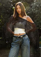 Poncho de tejido abierto en color negro con destellos brillantes, diseño asimétrico con flecos en los bordes.