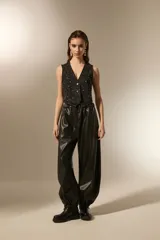 Babucha de cuero sintético color negro, con cintura elástica y puños ajustados en los tobillos. Presenta un diseño holgado y moderno con costuras horizontales en las piernas.