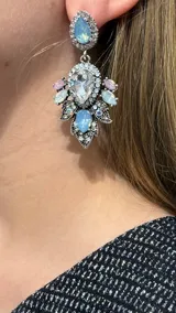 Caravanas colgantes de estilo barroco con base plateada, decoradas con cristales en tonos celestes, rosados y transparentes.