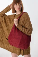 Bolso tipo hobo de cuero color bordó, con correa de hombro y forma circular.