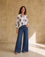 Camisa blanca de manga larga con estampado azul en contraste, cuello camisero y cierre frontal con botones.