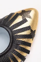 Zapatos tipo blucher artesanales de napa dorada con estampado de estrellas negras. Presentan un adorno de flecos de napa negra en el empeine, cierre con cordones y suela de cuero.