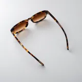 Lentes de sol Icon modelo Merlot, con armazón rectangular translúcido en tono marrón y cristales oscuros.