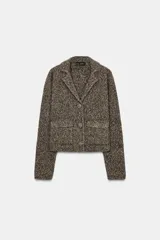 Chaqueta de punto con textura jaspeada, cuello solapa y manga larga. Presenta bolsillos delanteros de plastrón con solapa y cierre frontal con botones forrados a tono.