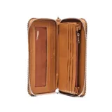 Billetera tipo fichero color habano, confeccionada en material textil con acabado gamuzado. Presenta un diseño rectangular con cierre perimetral decorado con tachas metálicas pequeñas en todo el borde. Incluye una correa de muñeca extraíble y un logo circular grabado en relieve en el centro.