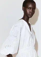 Vestido corto blanco de algodón con diseño broderie, escote en V con solapa, mangas cortas abullonadas y cintura elástica fruncida.