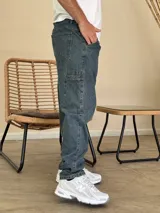 Pantalón tipo carpenter de denim azul con corte holgado, bolsillos laterales utilitarios y cierre frontal con botón.