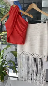 Falda tejida a mano en crochet, color crudo, con flecos en el ruedo y abertura lateral.