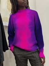 Buzo de tejido de punto en lana merino, con diseño oversize, manga ranglan y cuello levemente elevado. Presenta una textura de punto grueso y se destaca por sus colores vibrantes.