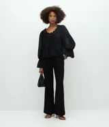 Pantalón de sastrería modelo wide leg, de tiro alto, confeccionado en tejido crepé. Presenta cierre frontal con botón y bolsillos traseros decorativos.