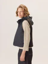 Chaleco con capucha, presenta una espalda de pelo sintético en color marrón oscuro con etiqueta de cuero negra y una capucha de tela tipo denim azul. Diseño original con mezcla de texturas.