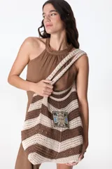 Bolso tejido a crochet con diseño a rayas horizontales en tonos marrón y beige. Tiene un parche cuadrado con el texto "Flowers Petra Club" y asas de hombro.