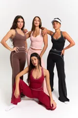 Conjunto deportivo compuesto por un top de escote redondo con breteles anchos y una calza larga de tiro alto. Ambas prendas son de color marrón con detalles de costuras blancas a contratono y el logo bk. estampado en el frente del top.
