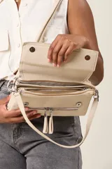Bandolera de ecocuero color beige con tapa frontal, cierre superior y correa regulable.