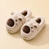 Pantuflas cerradas de peluche color beige con diseño de capibara, incluyendo orejas y nariz bordada. Cuentan con suela antideslizante.