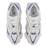 Championes urbanos New Balance modelo 9060, con diseño futurista inspirado en la estética de los años 2000. Presentan una combinación de tonos beige y blanco con detalles en azul, entresuela esculpida con tecnología de amortiguación ABZORB y SBS, y una capellada de materiales mixtos.