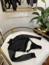 Conjunto de lencería compuesto por un top de cuello alto con mangas largas de microtul y detalles de encaje, y una tanga regulable de terciopelo y encaje.