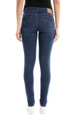 Jean de corte skinny y tiro medio, confeccionado en denim de tono azul oscuro con acabado uniforme. Presenta cierre frontal con botón y cremallera, además de bolsillos laterales y traseros clásicos.