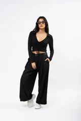 Crop top negro de manga larga con cuello polo, escote en V y detalle de frunce central ajustable con cordones.