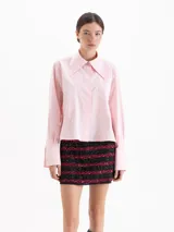 Camisa de poplín de algodón, color rosa claro, con corte holgado y largo hasta la cadera. Presenta cuello clásico con detalle de herraje metálico, cartera oculta con botones y puños con botones al tono.
