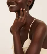 Set de 6 anillos plateados con diferentes diseños: tres con piedras de colores, uno texturizado, uno con strass y uno con un punto de luz.