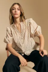 Camisa blanca de manga corta abullonada con terminación elastizada y cuello con leve frunce. Presenta una estampa floral integral.