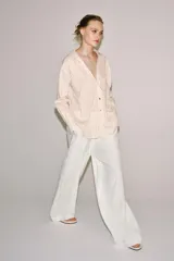 Camisa de mezcla de viscosa, color beige con rayas verticales rosadas, cuello solapa, manga larga con puños anchos, bajo redondeado y cierre frontal con botones.