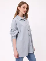 Camisa de corte oversize con efecto lavado, cuello clásico, cierre frontal con botones y mangas largas con puños rectos.
